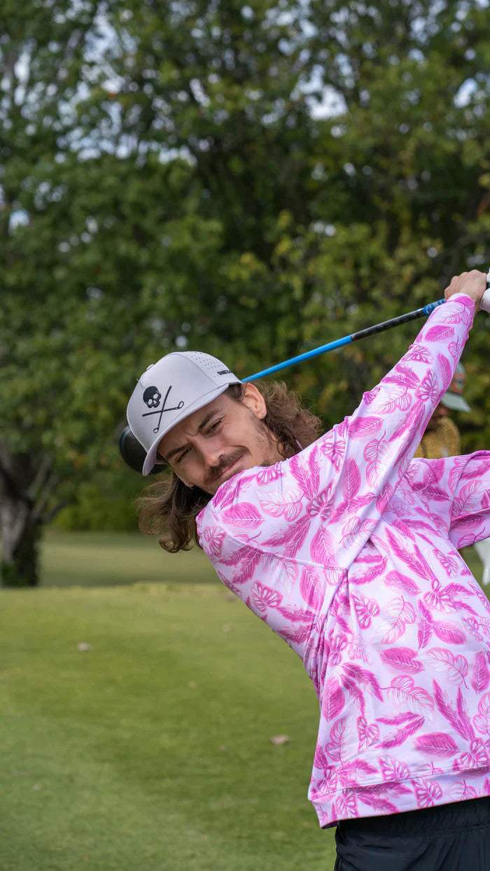 golfare med långt hår och en döskalle keps och lila långärmad golftröja.