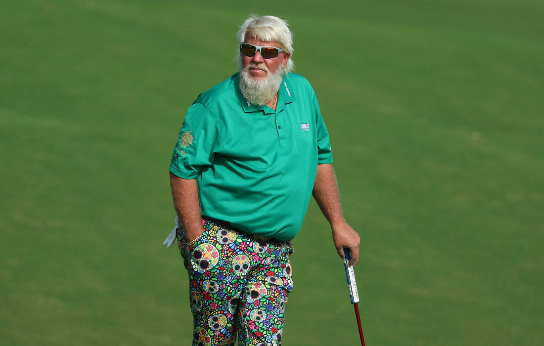 John Daly i en grön golfpiké och blommiga golfbyxor lutande mot en golfklubba.